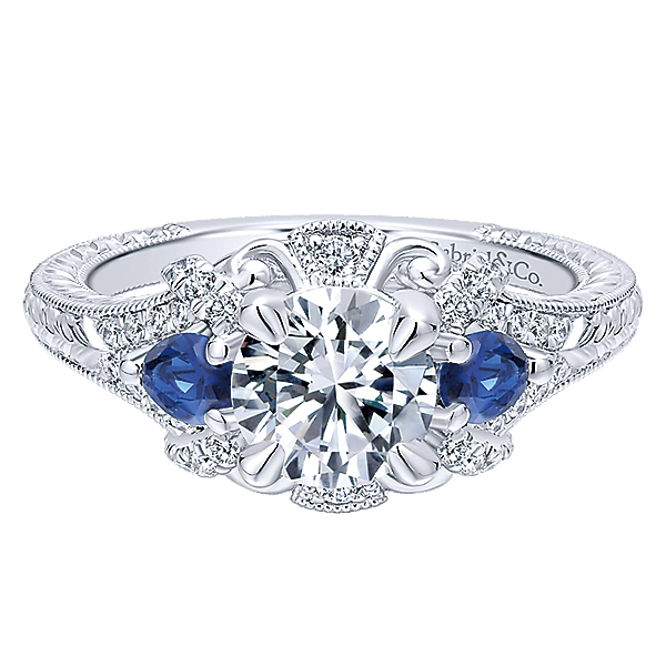 14Kw Sapphire & Diamond Semi-Mount 2S=.38Ct D=.23Ct    This antique-style engagement ring's grand halo boasts a pair of sapphire side stones in addition to diamonds and romantic white gold flourishes. A band with engraved details and milgrain bor