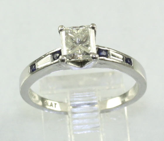 Estate Platinum Diamond And Sapphire Ring Having 1 Princess Cut Diamond Weighing Approximately 1.02 Carats And Graded Si2 For Clarity And H For Color  4 Prong Set In The Center With 2 Round Sapphires On Each Side Of The Center Having An Approximate Combin