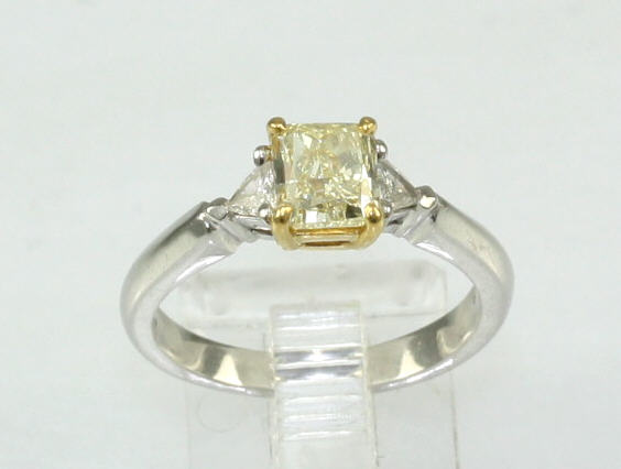 Estate Platinum Diamond Ring Having 1 IGI Certified Radiant Diamond Weighing 1.02 Carats  VS1-VS2 Natural Fancy Yellow Color  With 1 Trillion Diamond On Either Side Having A Combined Weight Of .12 Carat VS1-G Natural Fancy Yellow Center Stone Mounted In 2