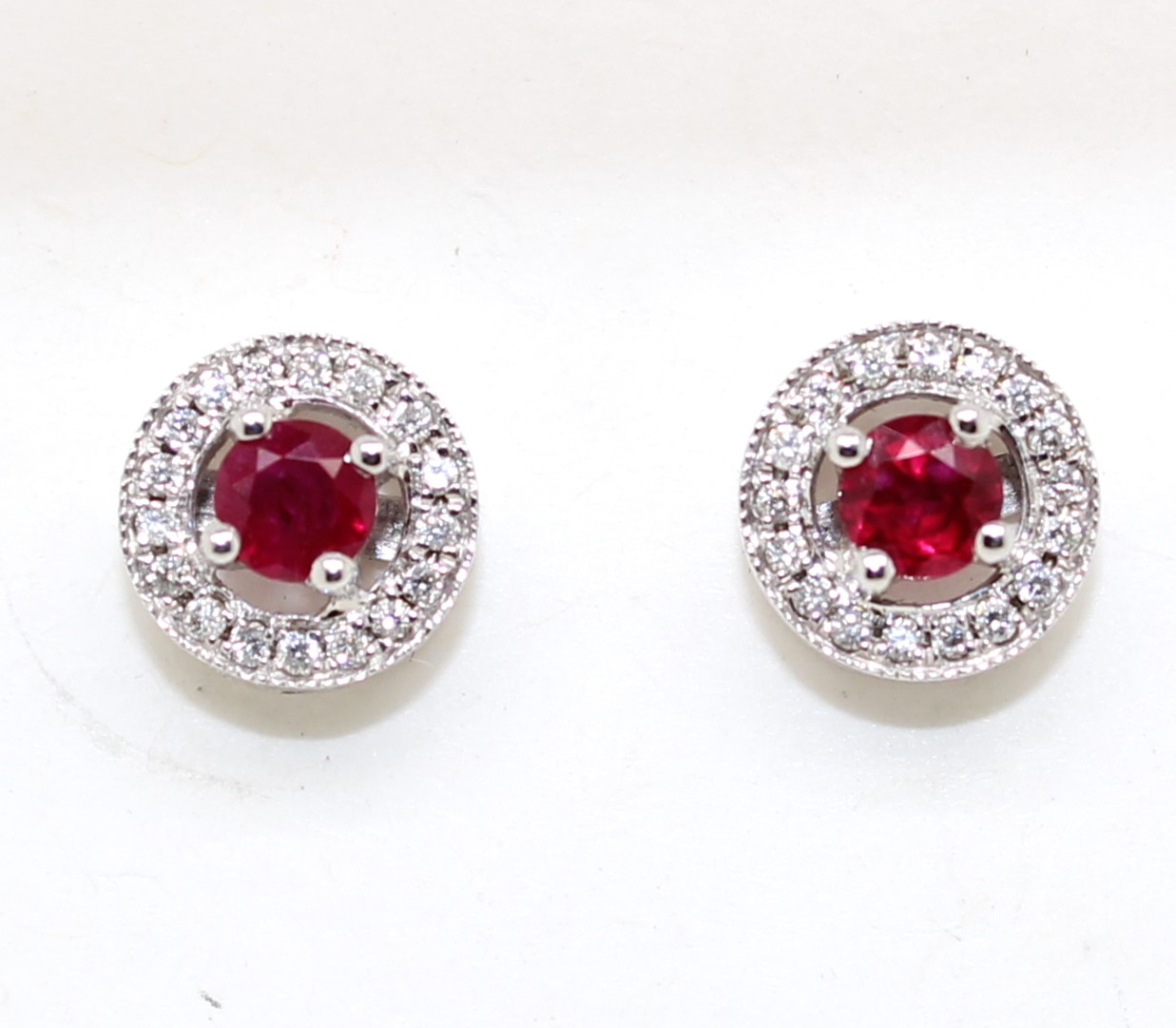 Each earring contains 1 round cut ruby prong set in the center surrounded by 17 full cut prong set diamonds. post and friction backs. 2 rubies = .56 carat 34 diamonds = .15 carat H-I SI1-2