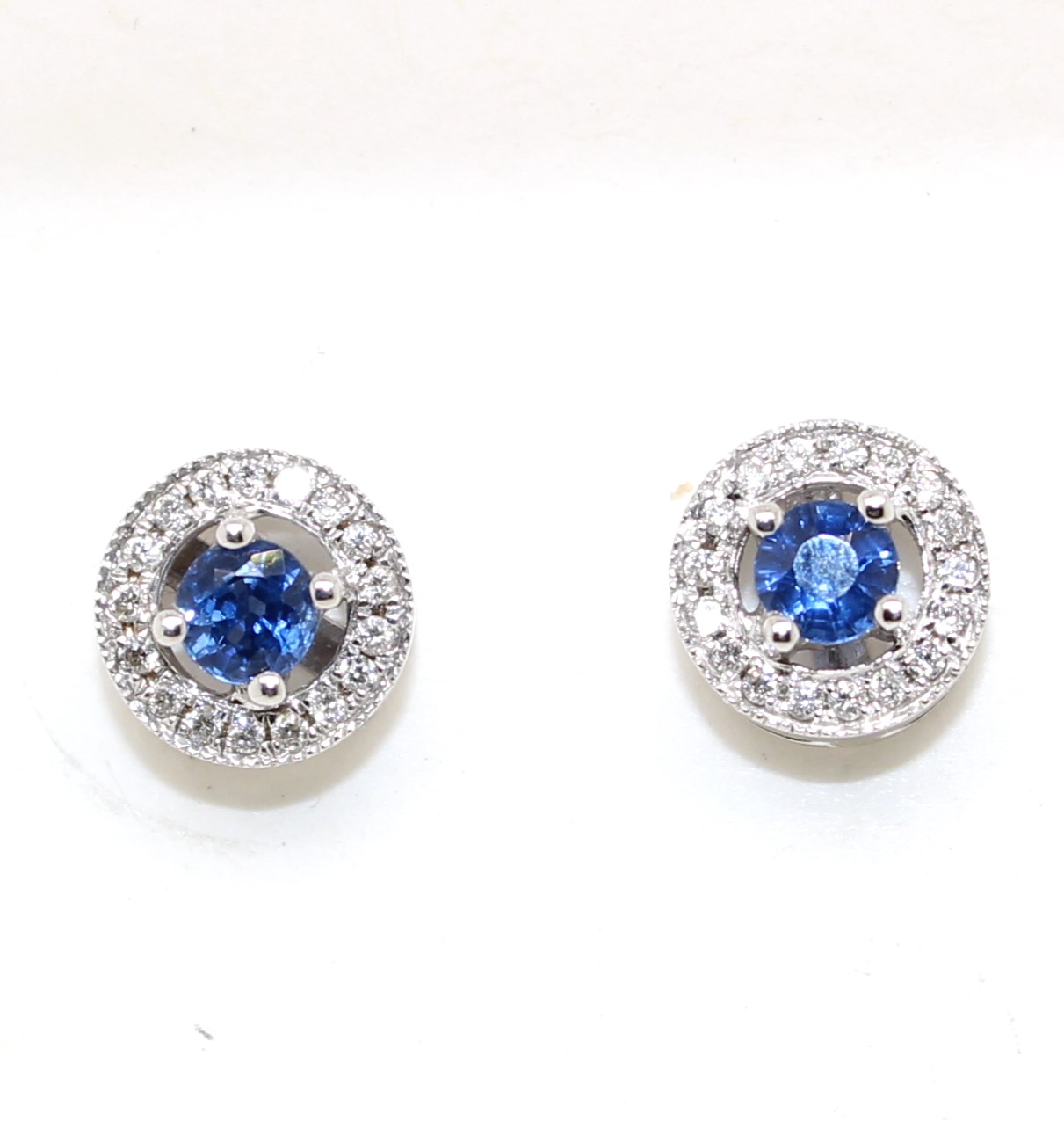 Each earring contains 1 round cut sapphire prong set in the center surrounded by 17 full cut prong set diamonds. post and friction backs. 2 sapphires = .58 carat 34 diamonds = .15 c